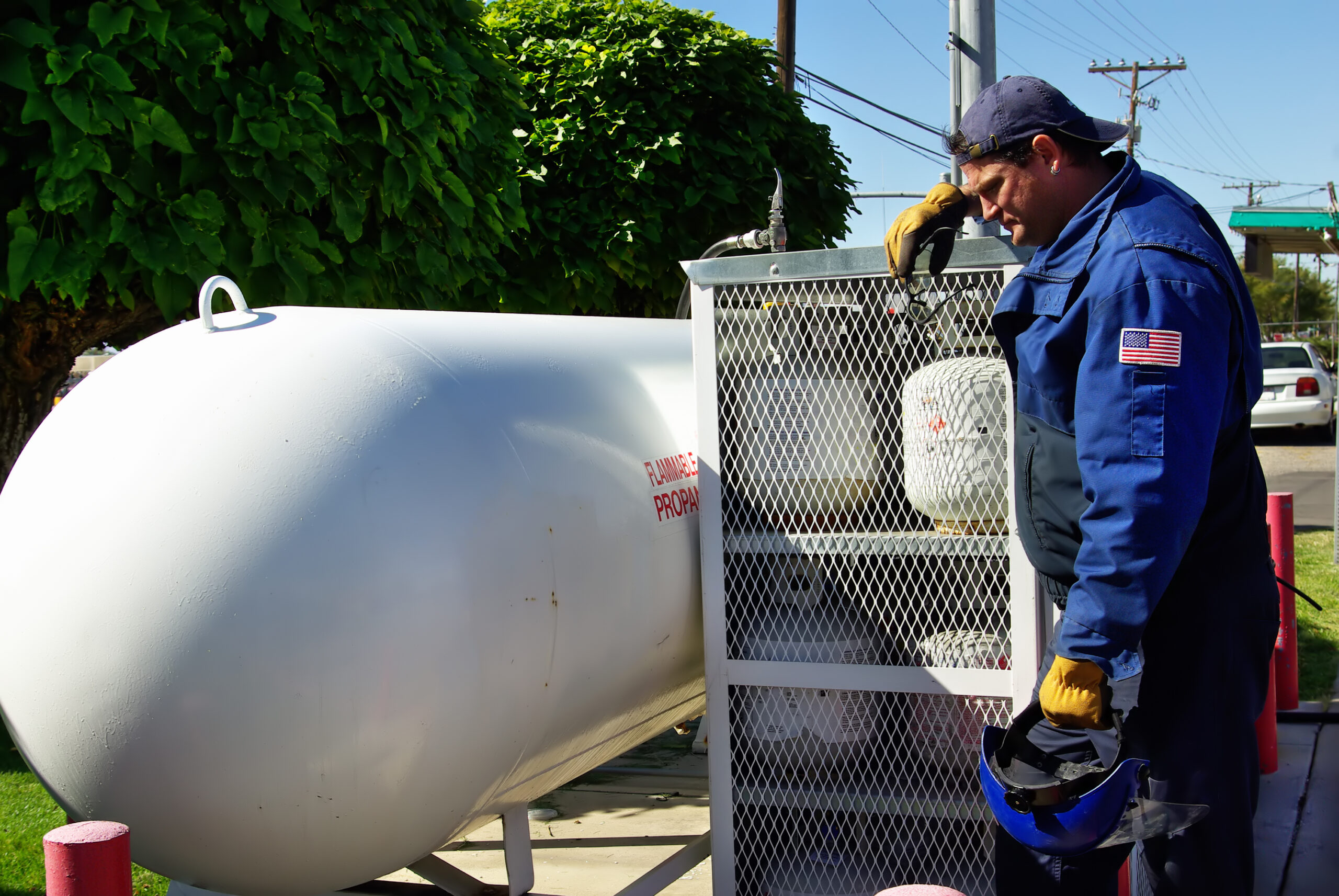 Worker leaning against natural gas tank cage